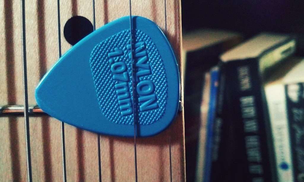 Nylon guitar picks on the strings of an electric guitar (decorative image).