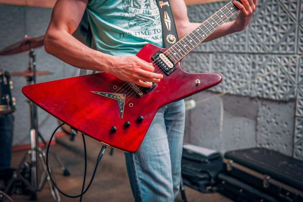 metaò guitar playing with a red 6 string electric guitar.